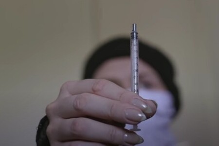 Девушка держит в руке шприц